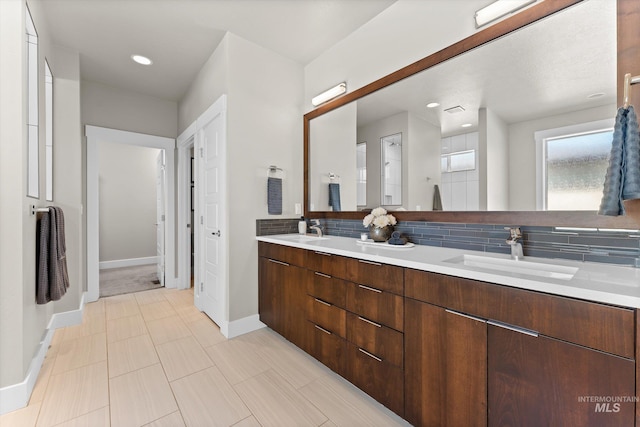 bathroom with baseboards, double vanity, and decorative backsplash