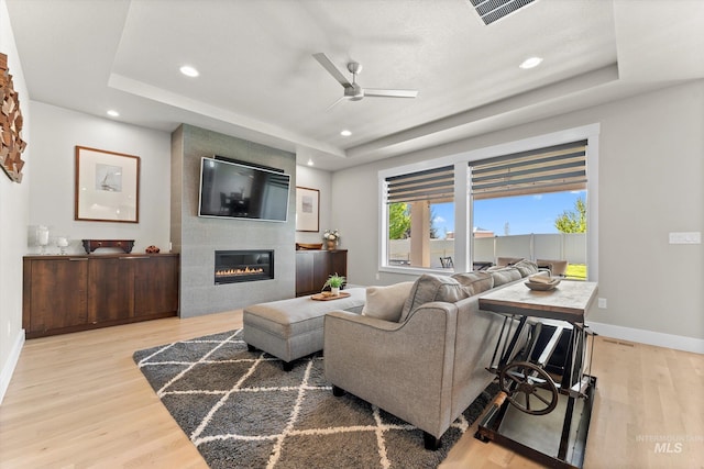 living room featuring a ceiling fan, a tray ceiling, wood finished floors, and recessed lighting