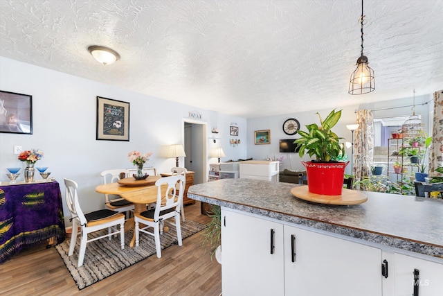 kitchen with white cabinets, a textured ceiling, and light wood finished floors