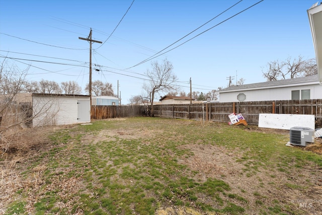 view of yard featuring an outbuilding, central AC unit, and a fenced backyard