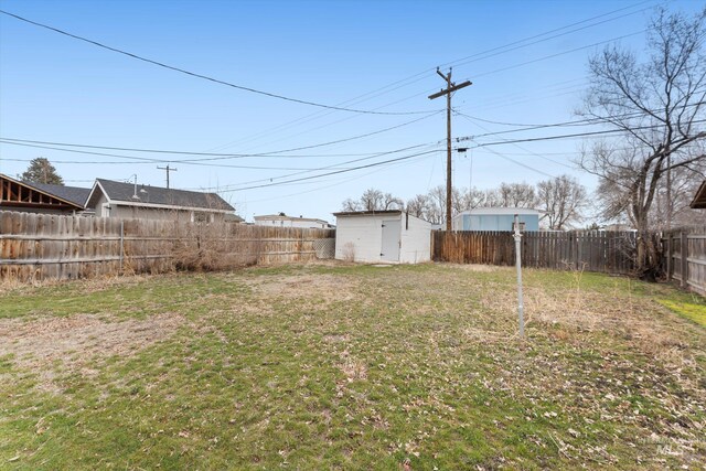 view of yard featuring a fenced backyard, a shed, and an outbuilding