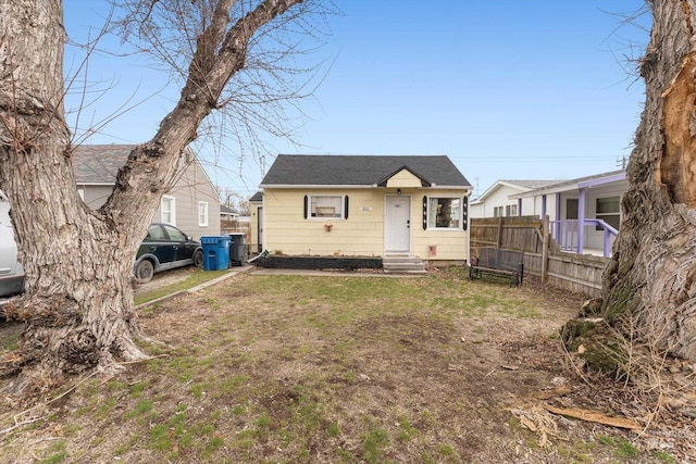 bungalow-style home featuring entry steps, a front yard, and fence