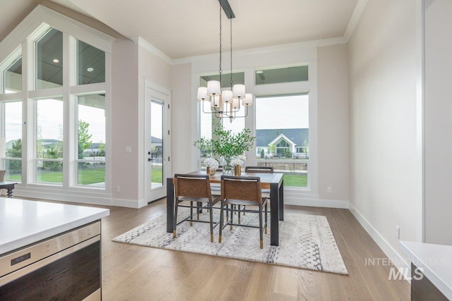 dining area with wood finished floors, a chandelier, ornamental molding, and baseboards