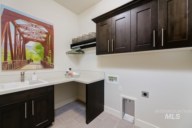 laundry area featuring cabinet space, electric dryer hookup, hookup for a washing machine, light tile patterned flooring, and baseboards
