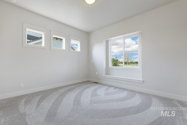 empty room featuring light colored carpet and baseboards