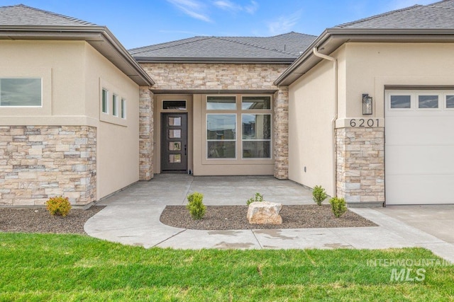 doorway to property with stone siding, an attached garage, stucco siding, and roof with shingles