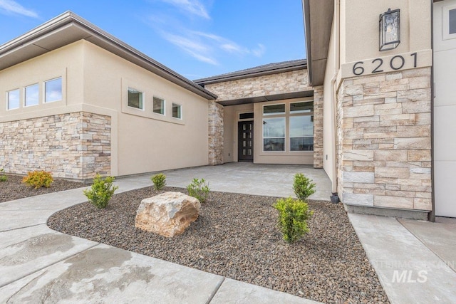entrance to property with stone siding and stucco siding