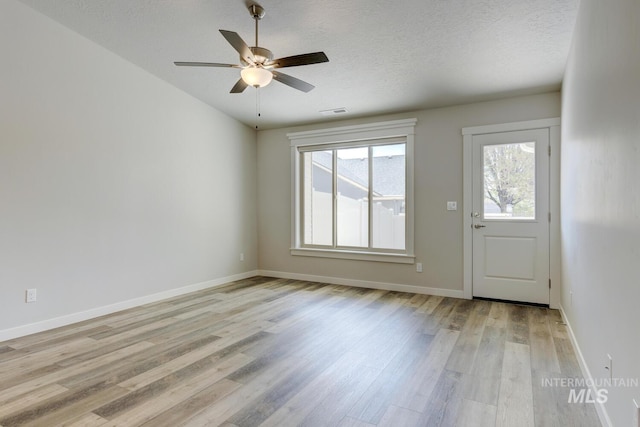 interior space with light wood-style floors, baseboards, ceiling fan, and visible vents