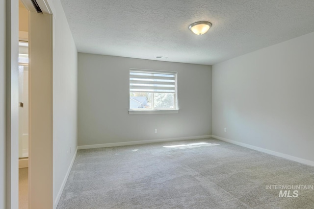 carpeted empty room featuring a textured ceiling and baseboards