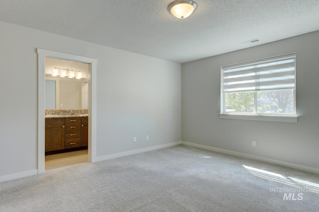 unfurnished bedroom featuring visible vents, a textured ceiling, baseboards, and light colored carpet