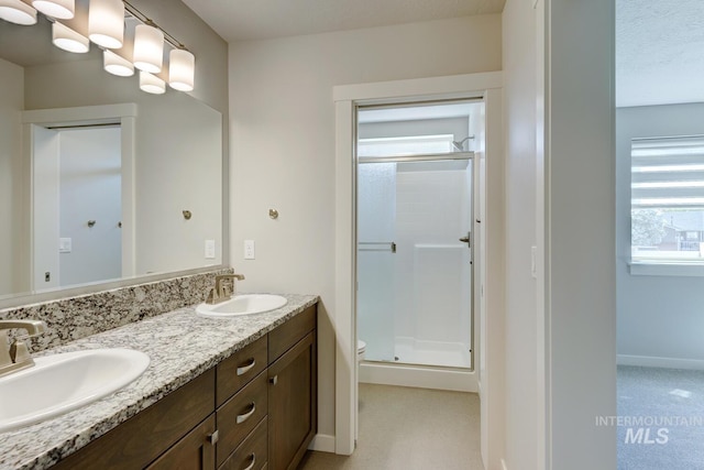 bathroom featuring a sink, a shower stall, and double vanity