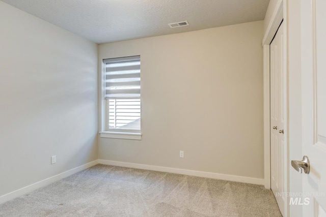 unfurnished bedroom featuring baseboards, light colored carpet, and visible vents