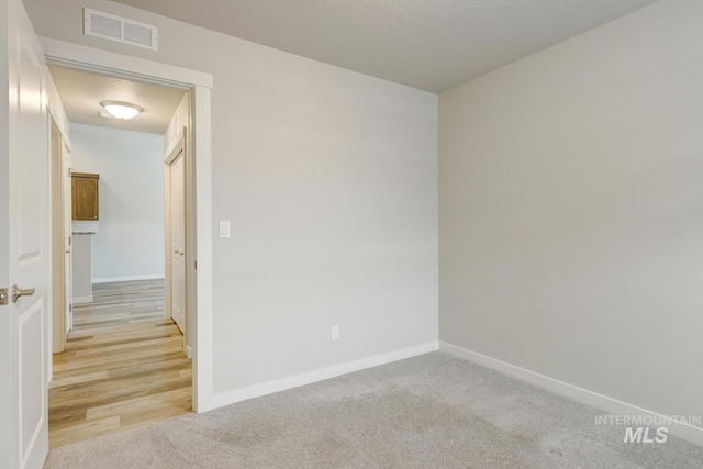 empty room featuring light colored carpet, baseboards, and visible vents