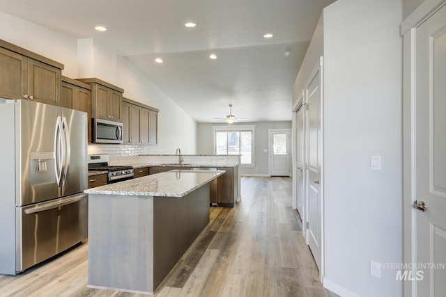 kitchen featuring ceiling fan, stainless steel appliances, a peninsula, lofted ceiling, and tasteful backsplash