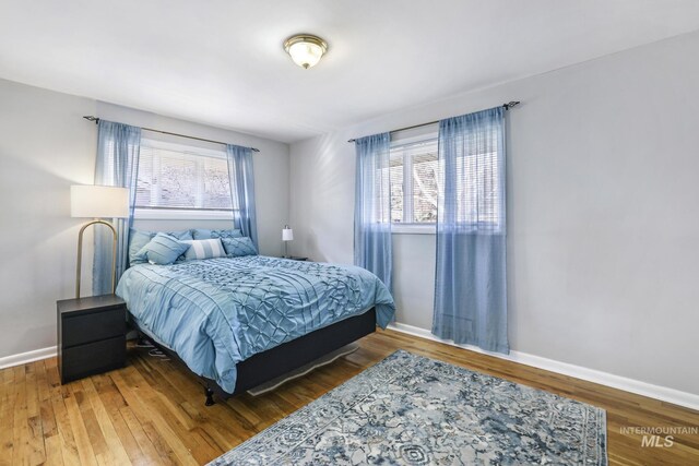 bedroom with baseboards, multiple windows, and wood finished floors