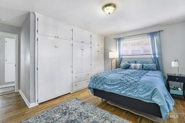 bedroom featuring baseboards, light wood-type flooring, and a closet