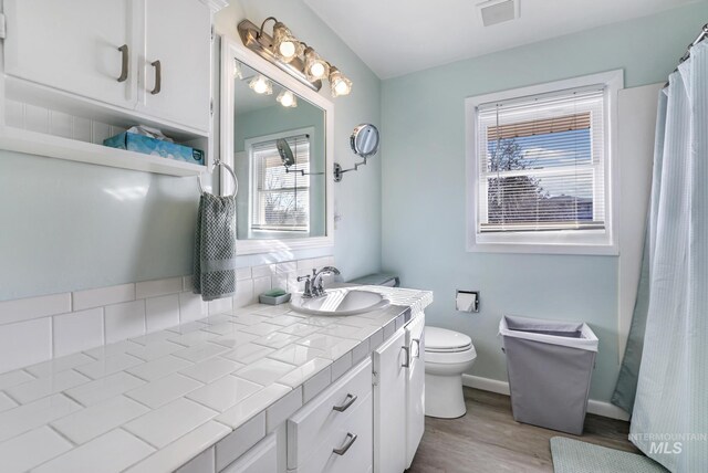 full bath featuring visible vents, baseboards, toilet, wood finished floors, and vanity