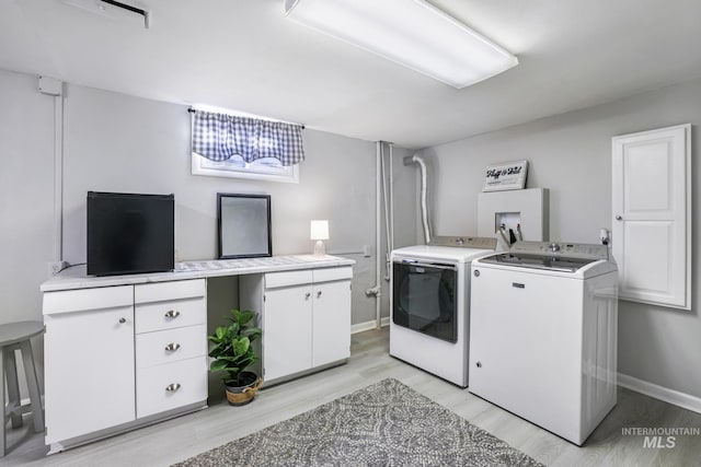 washroom with light wood-type flooring, cabinet space, baseboards, and washer and clothes dryer