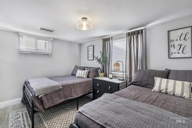 bedroom featuring visible vents, baseboards, and wood finished floors