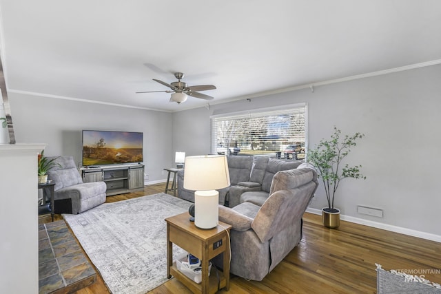 living room featuring ceiling fan, crown molding, baseboards, and wood finished floors