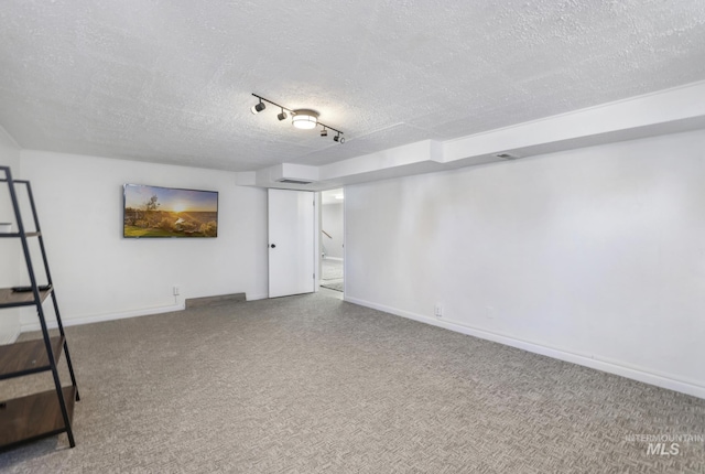 finished basement with carpet flooring, rail lighting, a textured ceiling, and baseboards