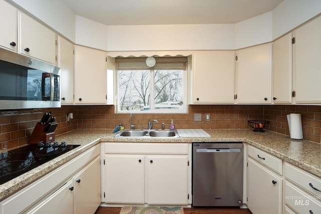 kitchen featuring a sink, stainless steel appliances, decorative backsplash, and light countertops