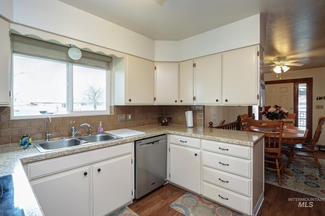 kitchen with tasteful backsplash, light countertops, dark wood-style flooring, stainless steel dishwasher, and a sink