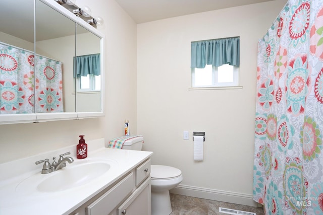 bathroom with vanity, toilet, baseboards, and a wealth of natural light