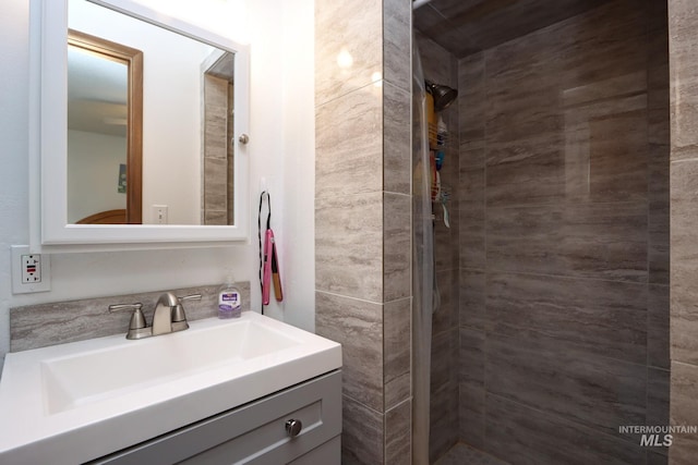 full bathroom with tiled shower and vanity