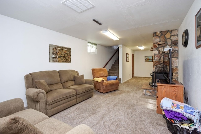 carpeted living area featuring visible vents, stairs, and a wood stove