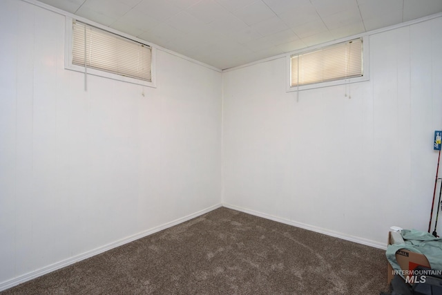 basement with dark colored carpet and baseboards