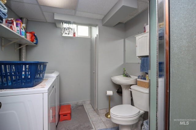 bathroom with tile patterned flooring, baseboards, toilet, independent washer and dryer, and a paneled ceiling