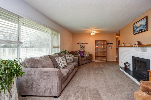 living area featuring a brick fireplace, a ceiling fan, carpet floors, and a textured ceiling