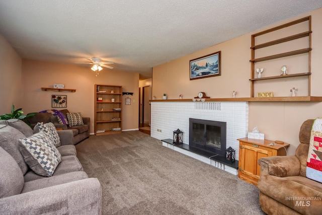 living area featuring ceiling fan, a brick fireplace, carpet, and a textured ceiling