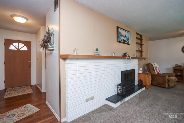 foyer with visible vents, a fireplace, a textured ceiling, and wood finished floors