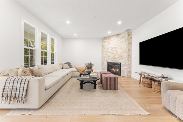 living room featuring a stone fireplace and light hardwood / wood-style flooring