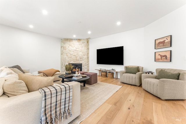 living room featuring a stone fireplace and light hardwood / wood-style flooring