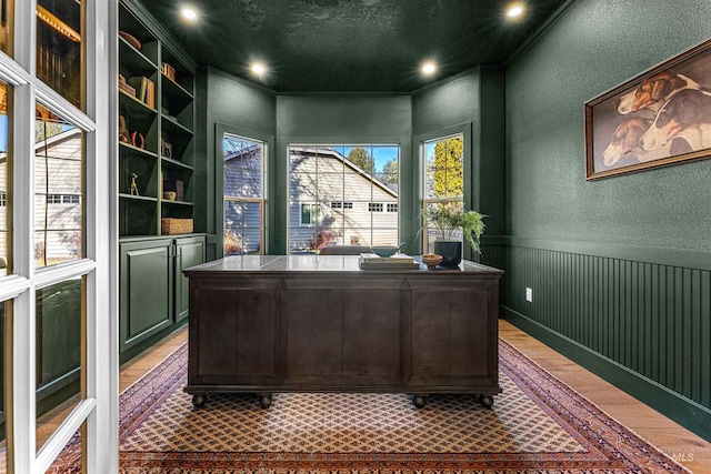 office space featuring built in shelves, ornamental molding, wood-type flooring, and a textured ceiling