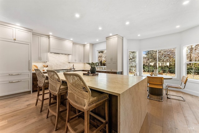 kitchen featuring a center island, a breakfast bar, decorative backsplash, and light wood-type flooring