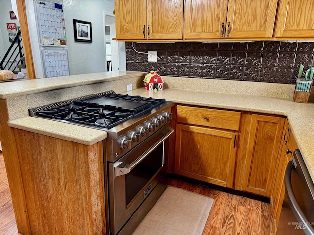 kitchen with kitchen peninsula, light wood-type flooring, backsplash, and stainless steel appliances