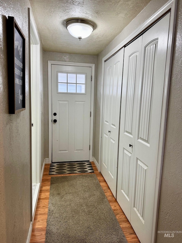 doorway to outside with wood-type flooring and a textured ceiling