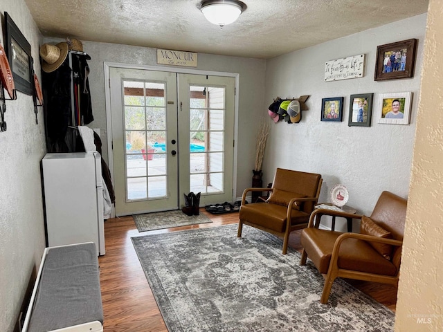 sitting room featuring a textured ceiling, french doors, and dark hardwood / wood-style floors