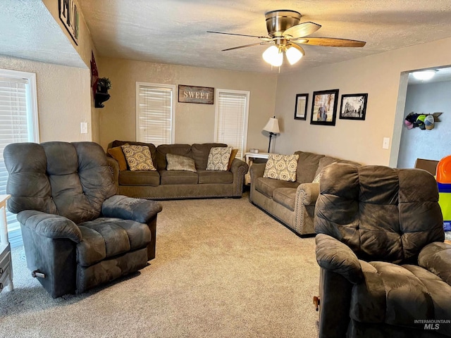 living room featuring ceiling fan, a textured ceiling, and light carpet