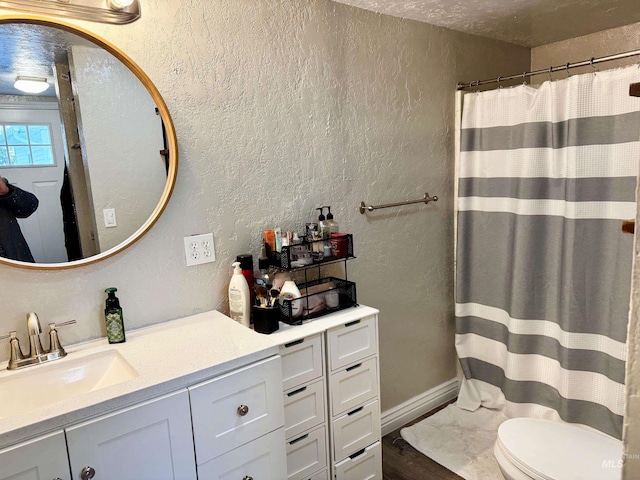 bathroom featuring a shower with curtain, vanity, toilet, and a textured ceiling