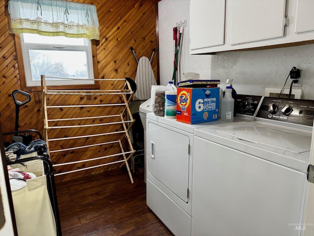 clothes washing area featuring washing machine and dryer, wood walls, dark hardwood / wood-style flooring, and cabinets