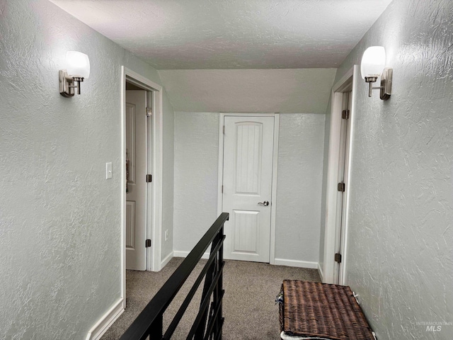 corridor featuring carpet, a textured ceiling, and lofted ceiling