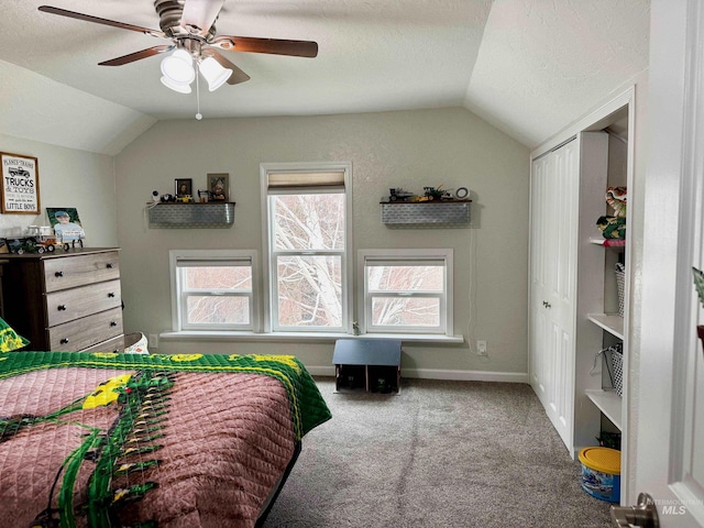 carpeted bedroom with a textured ceiling, ceiling fan, a closet, and vaulted ceiling