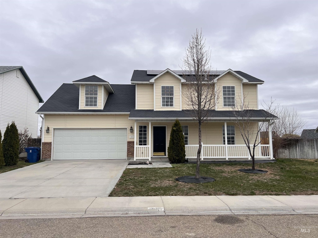 view of front of property featuring concrete driveway, a front lawn, a porch, solar panels, and a garage