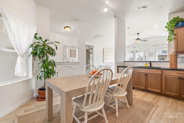 dining space featuring lofted ceiling, light wood-type flooring, and visible vents