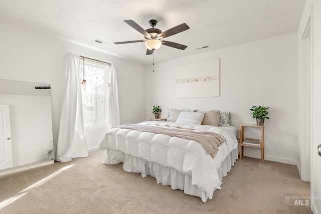 bedroom with baseboards, visible vents, a textured ceiling, and light colored carpet